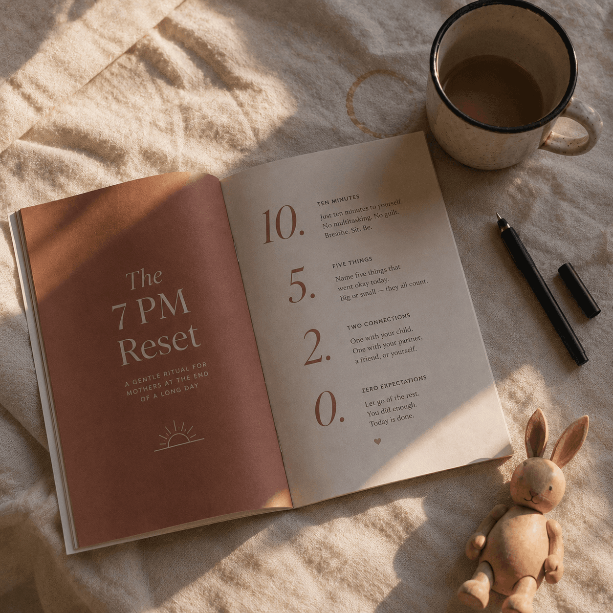 The 7 PM Reset booklet open on a linen tablecloth next to a mug of tea
